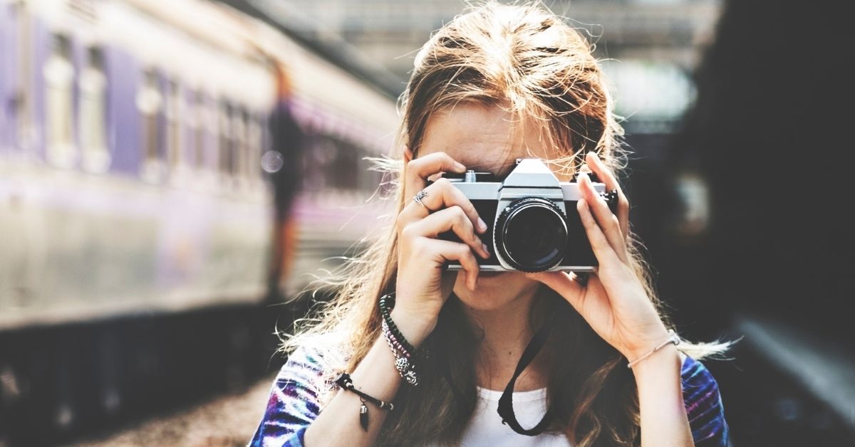 girl with camera and train in background